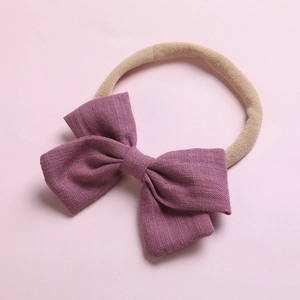 Détail de la texture en lin de l'arc violet et du bandeau élastique doux pour bébé en nylon