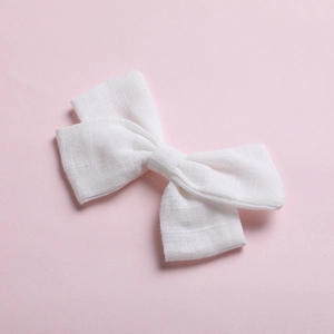 Detail shot of white cotton bow hair clip with textured fabric on pink background