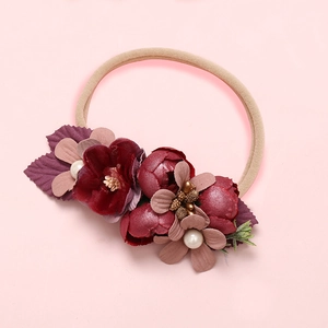 Détail d'un bandeau bébé avec fleurs en tissu rouge foncé et bande élastique en nylon