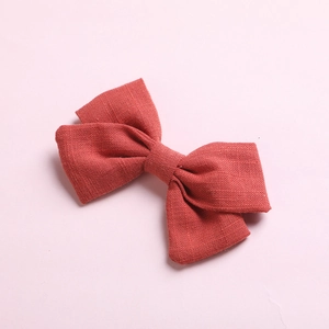 Pair of rust red cotton linen bow hair clips for girls with textured fabric on pink base