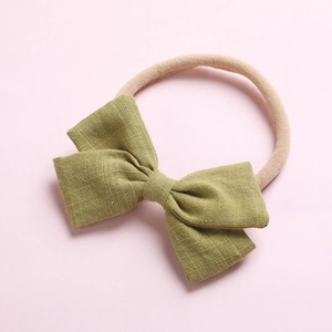 Détail du nœud en lin vert olive sur un bandeau bébé en nylon beige doux et sans couture