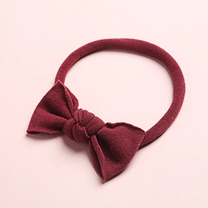 Détail d'un bandeau bébé en nylon rouge foncé avec nœud en maille côtelée