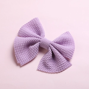 Close-up of lavender bow hair clip with textured waffle fabric on a pink background
