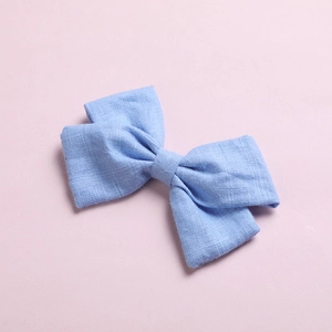 Detail of light blue bow hair clip with textured cotton fabric on pink background