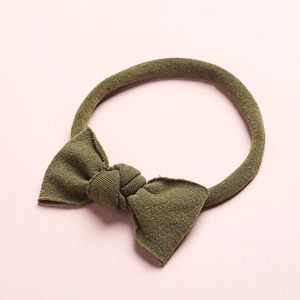 Gros plan du bandeau bébé en nylon vert olive sans couture avec nœud en maille douce