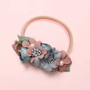 Détail d'un bandeau floral artisanal avec ruban en nylon souple et fleurs en tissu perlé