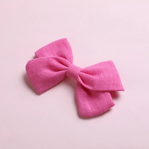 Detailed texture of rose pink cotton bow hair clip for girls on soft pink background