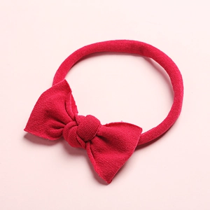 Détail d'un bandeau élastique en nylon pour bébé avec un gros nœud papillon rose fuchsia