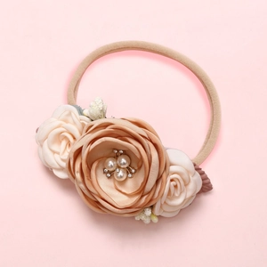 Détail d'un bandeau pour bébé avec fleurs en satin champagne, perles et strass brillants