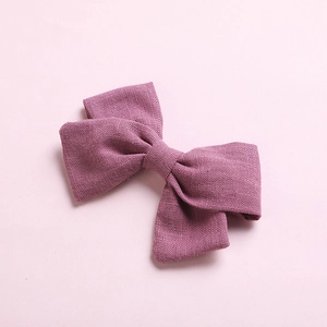 Detail shot of purple slub cotton bow hair clip showing textured fabric on pink background