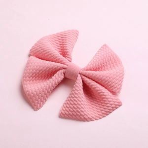 Detailed close-up of textured waffle fabric pink bow hair clip for babies and girls