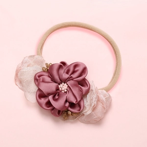 Détail du bandeau bébé avec fleur en satin rose poudré, résille dentelle et perles