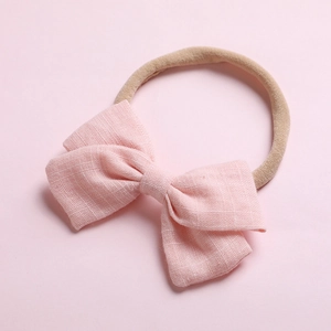 Gros plan du nœud en lin rose sur un bandeau en nylon souple pour bébés