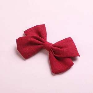 Macro detail of textured cotton bow hair clip in deep burgundy with rustic fiber pattern