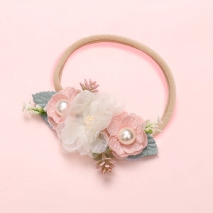Détail d'un bandeau bébé avec fleurs en dentelle rose, perles et ruban élastique