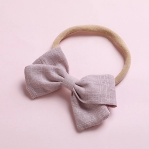 Détail d'un bandeau bébé avec un nœud en lin violet doux et un ruban en nylon