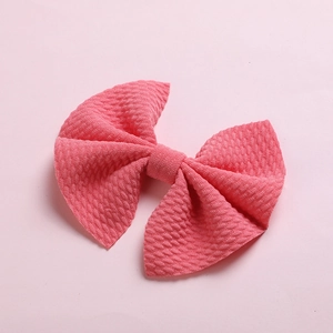 Detailed macro view of pink bubble fabric bow hair clip with waffle texture for infants