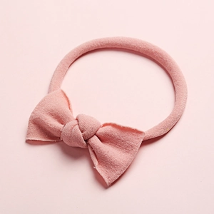 Bandeau bébé en nylon rose doux avec un joli nœud sur un fond pastel assorti