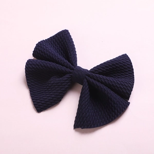 Detail of navy blue waffle texture fabric bow hair clip for children with grainy knit finish