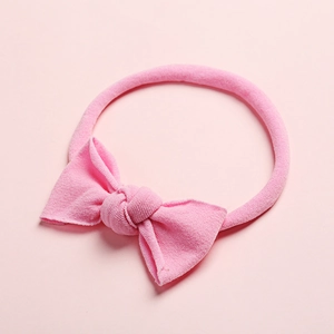 Détail du bandeau bébé en nylon côtelé rose avec un nœud doux noué à la main sur élastique