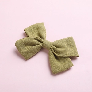 Detailed texture of olive green cotton linen bow clip on a soft pink background