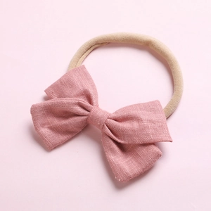 Détail d'un nœud en lin rose sur un bandeau souple pour accessoires bébé