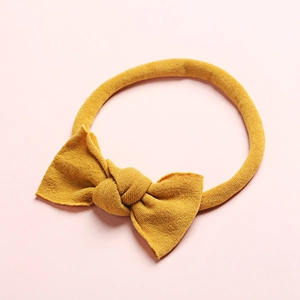 Détail d'un bandeau pour bébé en maille côtelée jaune moutarde avec nœud doux