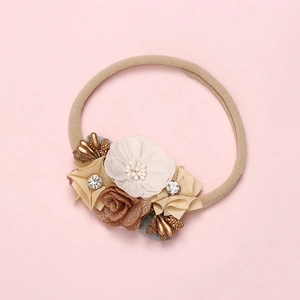 Detail of beige nylon baby headband with handmade silk flowers and golden berry accents