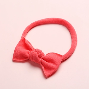 Vue détaillée du bandeau pour bébé en nylon rose corail avec tissu doux et nœud