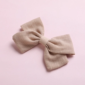 Detail shot of a natural cotton bow hair clip with textured fabric on pink background