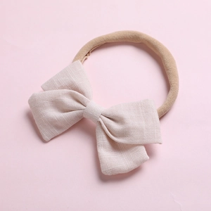 Détail du bandeau bébé avec nœud en coton beige et bande en nylon élastique souple