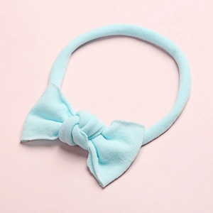 Détail d'un bandeau en nylon pour bébé avec un nœud tricoté bleu clair tout doux