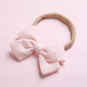 Détail d'un nœud en tissu rose doux et d'un bandeau en nylon élastique pour bébés