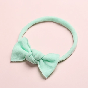 Vue détaillée d'un bandeau pour bébé vert menthe en nylon doux avec un nœud côtelé