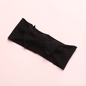 Detail of soft black nylon baby headband with a large elastic knit bow decoration