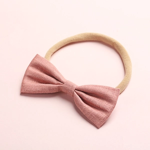 Dettaglio del fiocco in lino rosa e della fascia morbida in nylon per neonati su rosa