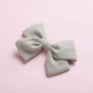 Detailed macro view of the natural linen fabric texture on a grey girl bow hair clip