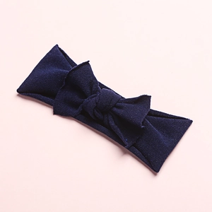 Close-up of soft navy blue nylon baby headband with delicate bow on pink background