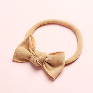 Gros plan du bandeau bébé en nylon souple avec un joli nœud sur fond rose vif