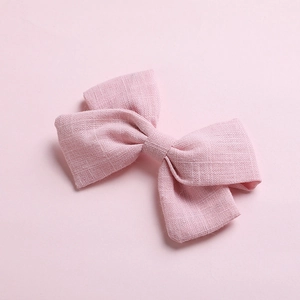 Detail of pink cotton bow hair clip with textured fabric on matching pink background