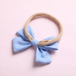 Détail du nœud en tissu bleu clair sur un bandeau en nylon beige haute élasticité