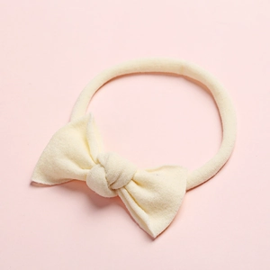 Gros plan du bandeau bébé en nylon crème avec un détail de nœud papillon fait à la main