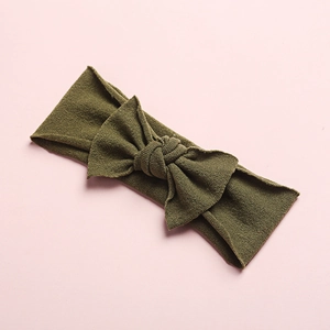 Detail of army green knitted baby headband with a large bow on a soft pink background