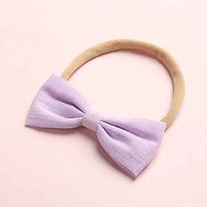 Dettaglio del fiocco in lino viola con fascia in nylon color carne per neonati