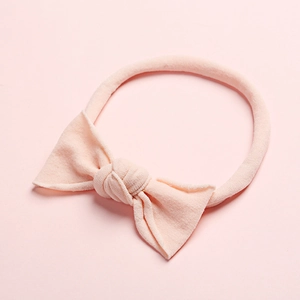 Détail d'un bandeau pour bébé rose pâle doux avec un nœud élastique en nylon souple