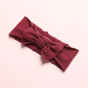 Detail of burgundy ribbed knit baby headband featuring a soft decorative bow design