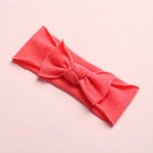 Detailed macro view of coral red ultra-soft nylon baby headband with knitted bow texture