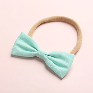 Dettaglio del fiocco in lino verde menta su fascia in nylon beige alta elasticità