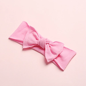 Close-up of pink soft nylon baby headband featuring a delicate bow on a matching background