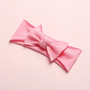 Detail of soft light pink baby headband with large nylon bow and textured fabric weave